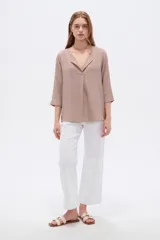 Blusa de viscosa color beige topo, con cuello en V amplio, solapas integradas y mangas tres cuartos de corte holgado.