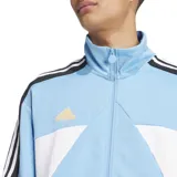 Campera Adidas de acetato celeste con detalles en blanco y negro. Presenta cierre frontal, cuello alto, bolsillos laterales y las tres tiras características de la marca en las mangas.