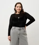 Blusa de manga larga confeccionada en tul con efecto aterciopelado. Presenta un diseño ajustado con escote canoa e incluye una anágua interna para mayor cobertura.