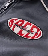 Campera biker de cuero sintético negro con detalles en blanco, cuello mao con broche, cierre frontal y parches bordados en el pecho. Presenta diseño acolchado en los hombros y mangas largas.