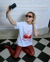 Remera blanca de algodón con cuello redondo y mangas cortas. Estampado frontal de dos cerezas rojas con la frase "Cherry Bomb!".