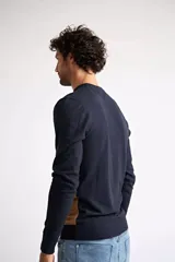 Sweater de punto con diseño color block, combinando azul marino en la parte superior, un patrón geométrico en tonos bordó y azul en el centro, y color camel en la parte inferior. Presenta cuello redondo y mangas largas.