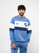 Buzo de felpa Umbro del Club Nacional de Football, con diseño de bloques de color en azul, blanco y azul marino. Presenta cuello redondo, puños y ruedo acanalados, con el logo de la marca y el escudo del club bordados en el pecho.