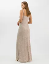 Vestido largo de encaje color beige, con escote recto decorado con pedrería y perlas, tirantes anchos y tajo lateral en la falda.