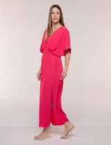 Vestido largo amarillo de corte fluido con escote en V, mangas cortas amplias y apliques de tachas en el escote y puños. Posee cintura elastizada fruncida y falda larga con tajos laterales en el ruedo.