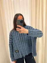 Sweater de punto con diseño de rayas verticales en relieve y textura trenzada, color terracota y beige. Presenta cuello redondo, corte holgado y diseño cropped.