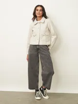 Chaqueta corta de paño color azul oscuro, con cuello camisero, cierre frontal con botones metálicos dorados y bolsillos frontales con solapa.