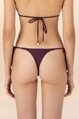 Calzón de bikini color violeta con tiritas laterales ajustables y detalle de cuentas doradas en los extremos.
