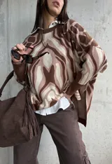 Sweater de tejido de punto con diseño estampado abstracto en tonos marrones y beige, de corte oversize, cuello redondo y mangas largas con puños acanalados.