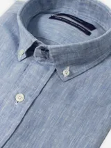 Camisa de lino celeste de manga larga con cuello abotonado y cierre frontal de botones.