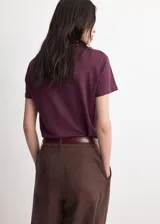 Camiseta de lino color bordó, de diseño recto, con cuello redondo y manga corta.