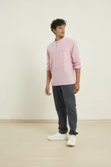 Camisa de lino color rosado, con cuello mao y cierre frontal parcial con botones. Presenta mangas largas y un bolsillo pequeño en el pecho.