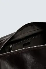 Bolso bandolera de piel color marrón oscuro, con solapa y cierre de imán y cremallera. Incluye un bolsillo interior con cremallera y un bolsillo plano. Tiene asa de hombro ajustable.