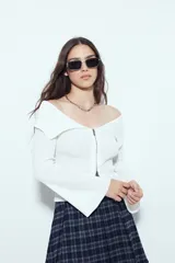 Top de punto acanalado negro, con diseño off-shoulder y escote amplio. Presenta mangas largas y cierre frontal completo con doble cursor, permitiendo ajustar la apertura superior e inferior.