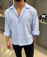 Camisa de corte relajado, color celeste pastel, con cuello cubano y mangas largas arremangadas.