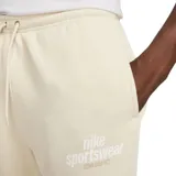 Pantalón de jogging color crema, de corte ajustado, con cintura elástica y cordón ajustable. Tiene bolsillos laterales y logo de Nike bordado en blanco en el muslo izquierdo.