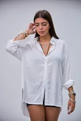 Camisa blanca de manga larga, con cuello clásico y botones frontales. Presenta puños anchos y un corte holgado.