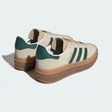 Championes Adidas Gazelle Bold color beige con las tres tiras clásicas en verde oscuro y suela de goma marrón con plataforma.