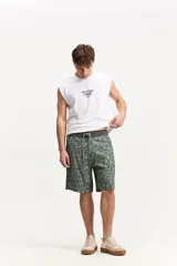 Short de baño estilo surf color verde militar con estampado geométrico abstracto, cintura con cordón ajustable y bolsillo trasero con solapa.