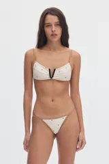 Top de bikini ajustable de color blanco crema con estampado de lunares negros, detalles de vivos en contratono camel y escote en V con ribete negro.