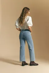 Jean de corte recto y tiro medio, confeccionado en denim elastizado de color negro. Presenta un diseño clásico con cierre de botón y cremallera, bolsillos laterales y traseros, y ruedo con terminación deshilachada.