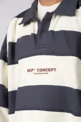 Buzo tipo polo de corte boxy con diseño de rayas horizontales anchas en color azul y blanco. Presenta cuello camisero, cierre frontal parcial con botones y logo estampado en el pecho.