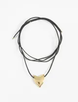 Gargantilla con cordón negro y dije dorado en forma de corazón.