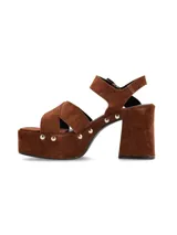 Sandalias de plataforma color marrón, con tiras cruzadas en el empeine, pulsera con hebilla al tobillo, taco cuadrado y detalle de tachas plateadas.