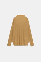 Jersey de punto con textura, color crudo, de cuello subido y manga larga. Presenta un diseño holgado con bajo asimétrico y aberturas laterales.