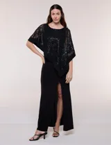 Vestido largo azul marino de seda fría, compuesto por una falda recta con tajo frontal y una capa superior superpuesta de encaje con lentejuelas bordadas, escote a la base y mangas tres cuartos acampanadas.