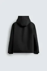 Cazadora técnica regular fit de color negro, con interior ligeramente acolchado. Presenta cuello subido con capucha ajustable, cierre frontal de cremallera oculta por solapa con botones a presión, bolsillos laterales y puños con interior de rib.