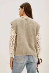 Chaleco de punto color beige, con cuello redondo y volados.