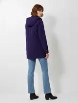 Gabardina impermeable de mujer, color morado oscuro, con capucha desmontable y cierre frontal oculto con botones a presión. Presenta bolsillos delanteros y ajuste interno en la cintura.