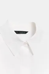 Camisa roja de cuello solapa, con mangas cortas abullonadas tipo globo y cierre frontal con botones ocultos.