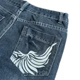 Pantalón de jean azul con estampado de un dragón blanco en la pierna derecha, corte recto y tiro bajo.
