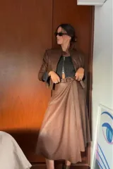 Falda midi color marrón chocolate, de cuero sintético, con corte evasé, cintura alta y cinturón con hebilla circular.