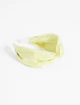 Vincha rígida color amarillo pastel, forrada en tela de poliéster con nudo superior.