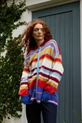Campera de punto con cierre frontal, diseño de rayas horizontales multicolores y textura suave. Cuenta con cuello alto y mangas largas.
