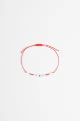 Pulsera ajustable con cordón rojo, decorada con abalorios dorados, cuentas rosadas y un dije central en forma de ojo turco.