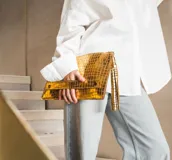 Sobre de fiesta dorado con textura tipo piel de cocodrilo y cierre con broche imantado.