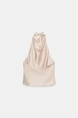 Top de cuello halter con escote fluido y caída suave. Presenta cierre con botones en la parte posterior y diseño sin mangas.
