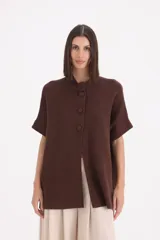 Saco de punto color chocolate, con cuello redondo, cierre frontal de tres botones y mangas cortas con dobladillo.