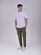 Jogging color gris oscuro, con cordón ajustable en la cintura, bolsillos laterales y bolsillos cargo en los muslos. Presenta un estampado discreto en el bolsillo cargo izquierdo.