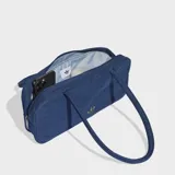Bolso tipo airliner de Adidas confeccionado en tejido denim azul. Presenta un diseño alargado con manijas largas para llevar al hombro, cierre principal y logo del Trifolio metálico en la parte frontal.