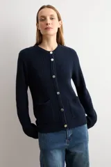 Chaqueta tejida de punto acanalado en color azul marino, con cuello redondo, cierre frontal de botones metálicos y dos bolsillos delanteros aplicados.