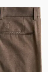 Pantalón de vestir de corte estándar, color marrón, con cierre de botón y corchete ocultos, bolsillos laterales y bolsillos traseros ribeteados.