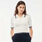 Sweater de punto canalé en color blanco, con cuello tipo polo, cierre frontal de tres botones dorados y detalles de rayas en contraste en el cuello, mangas y ruedo.
