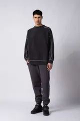 Buzo de cuello redondo con calce oversize, confeccionado en frisa de algodón con efecto de lavado gastado. Presenta costuras a contratono visibles y diseño de recortes en los hombros y mangas.