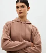 Buzo deportivo oversized con capucha, confeccionado en mezcla de algodón y poliéster. Presenta bolsillo frontal tipo canguro, mangas con recortes en los hombros y puños y ruedo con terminación en rib.