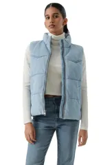 Chaleco acolchado tipo puffer con diseño western, confeccionado en denim de lavado claro. Presenta cuello alto, cierre frontal con cremallera y costuras horizontales.